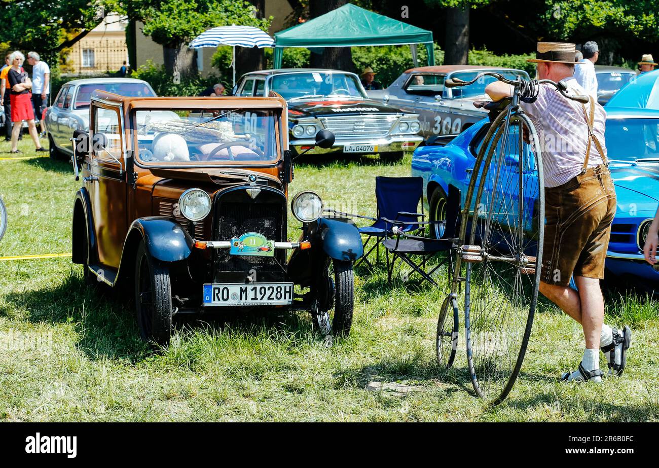 Maxlrain, Germany. 08th June, 2023. A unicyclist looks at a BMW Dixi from the 1930s at southern Bavaria's largest classic car meeting in front of the almost 500-year-old Maxlrain Castle. Credit: Uwe Lein/dpa/Alamy Live News Stock Photo