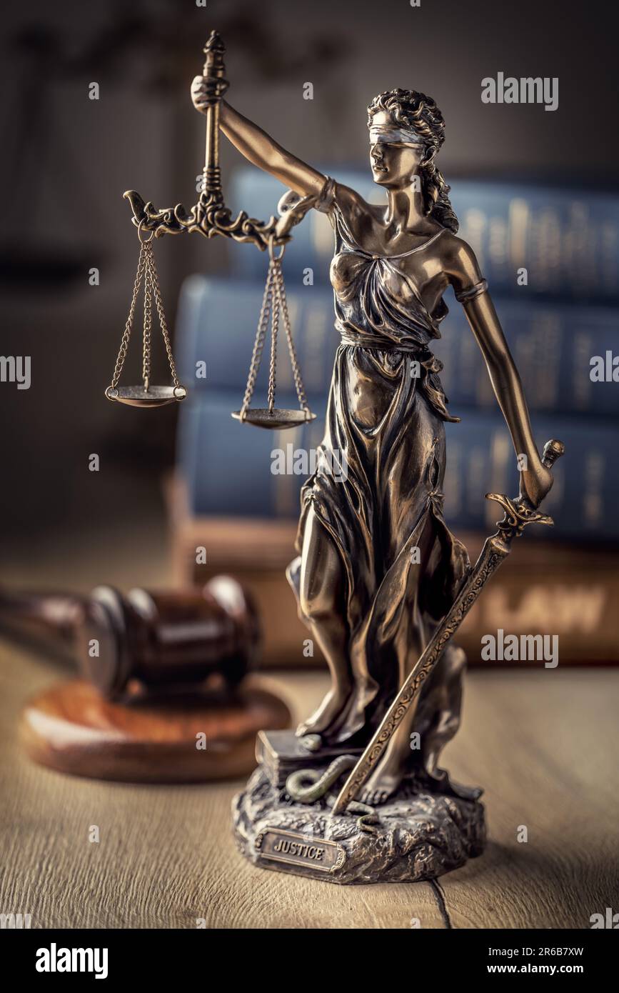 Statute of Justice and law books in the background. Stock Photo
