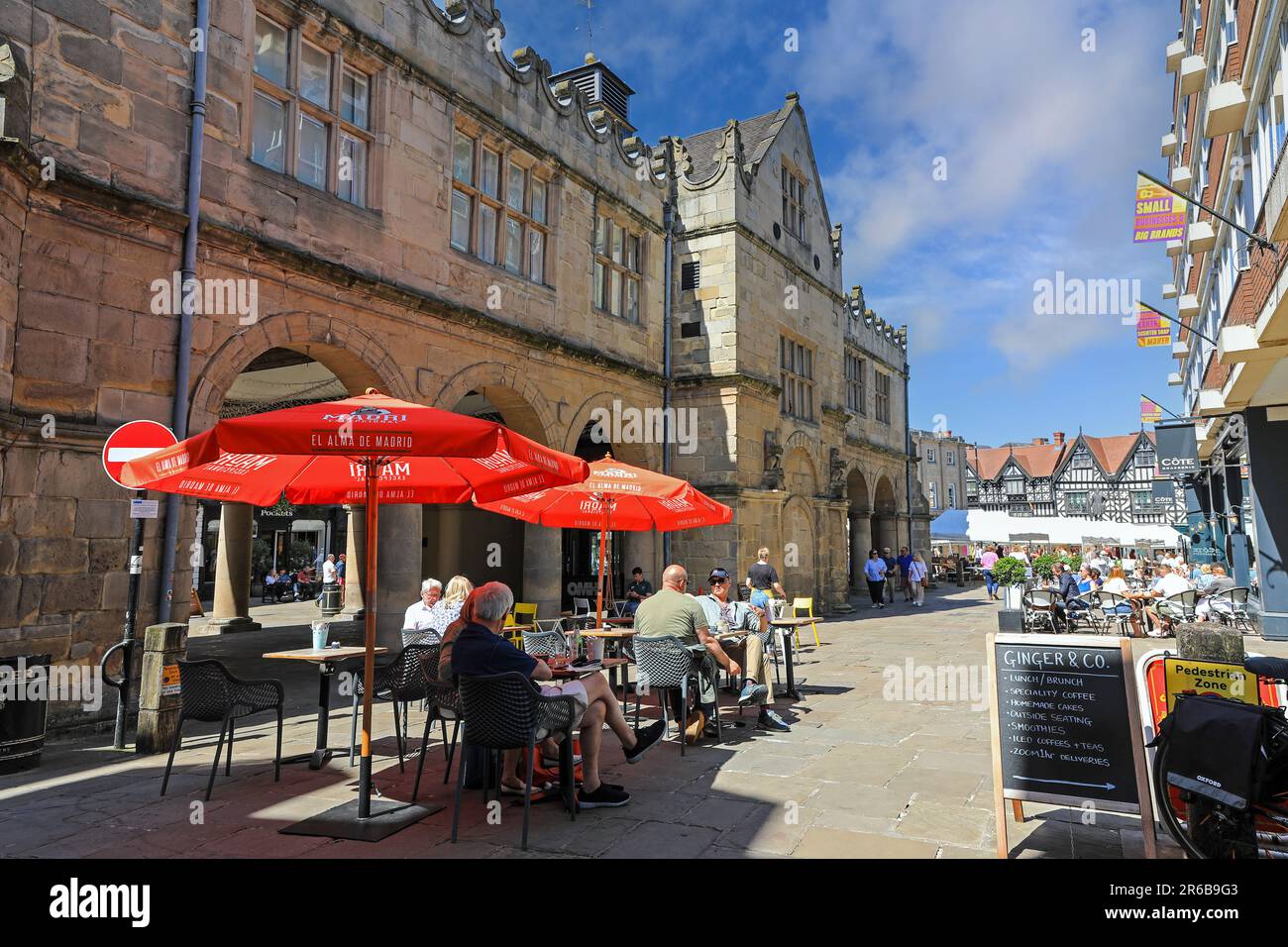 People sitting eating and drinking outside the Old Market Hall in the Town centre, Shrewsbury, Shropshire, England, UK Stock Photo