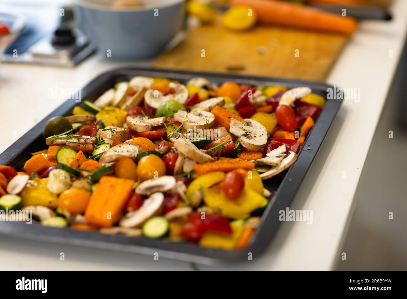 Seasoned chopped vegetables in baking tray on kitchen countertop Stock Photo
