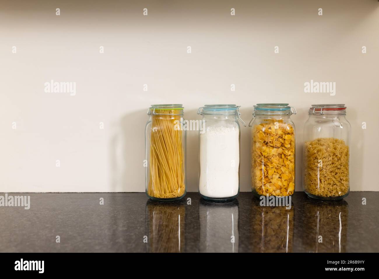 Storage jars of flour and varieties of pasta on kitchen countertop