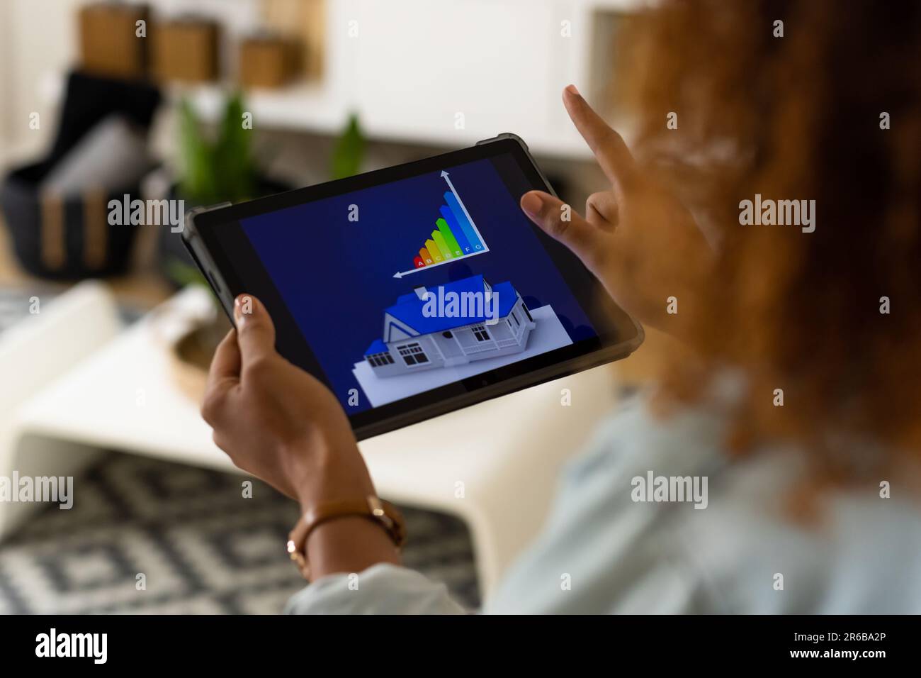 Biracial woman in living room at home using tablet with smart home ...