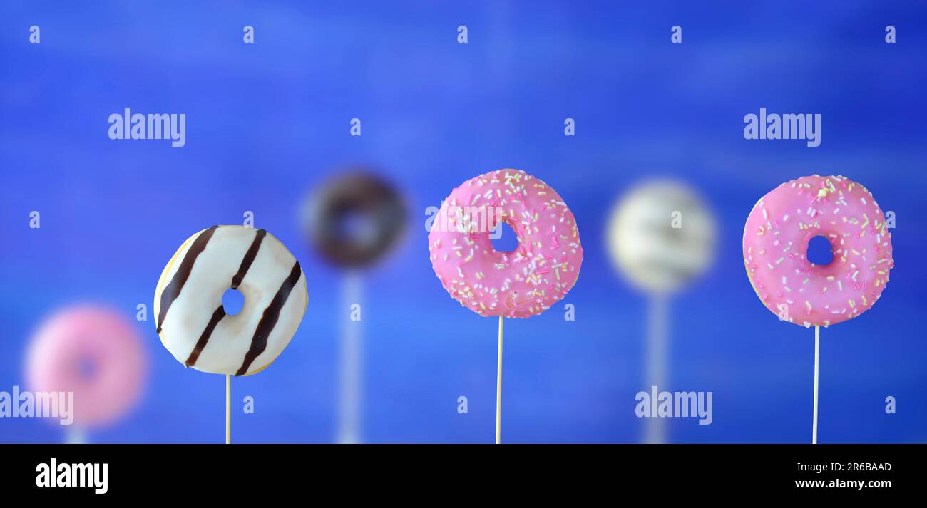 row of sweet donuts, some blurred in the background, snacks, sweets and junk food concept, free copy space Stock Photo