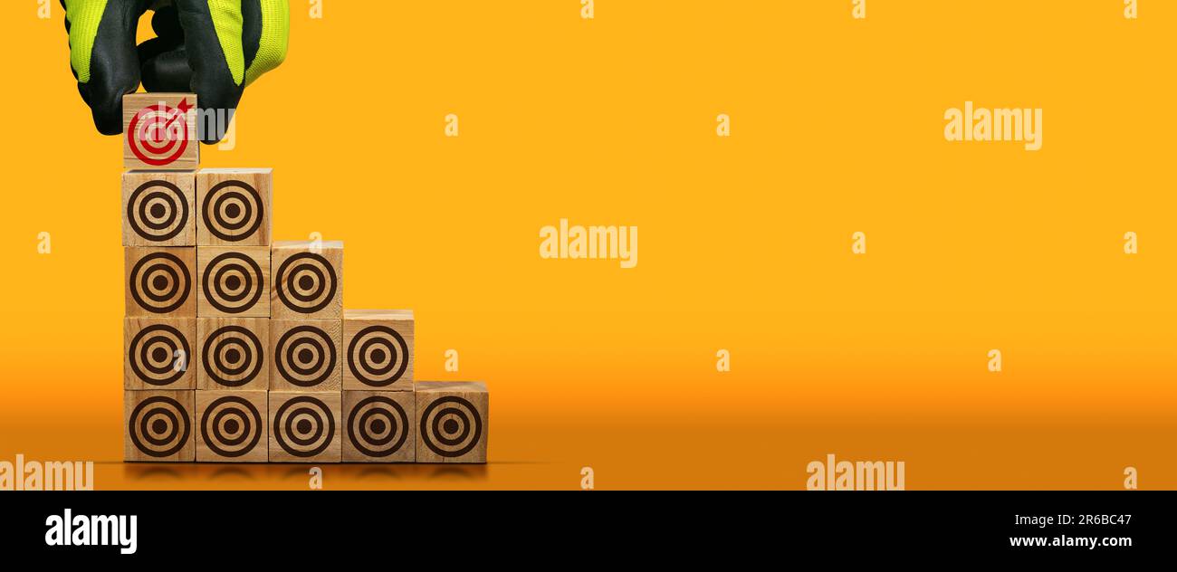 Gloved hand arranging wood blocks with many empty brown targets and one ...