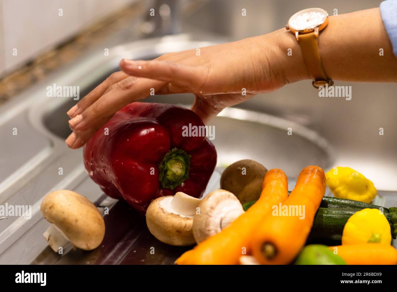 Hand of biracial woman washing vegetables in kitchen sink Stock Photo