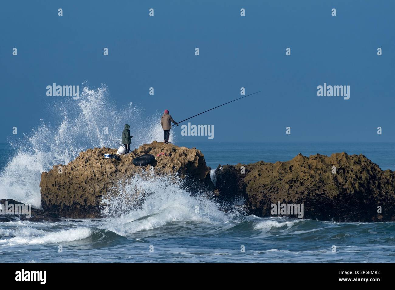 Fishermen on the rocks at Oualidia in Morocco Stock Photo