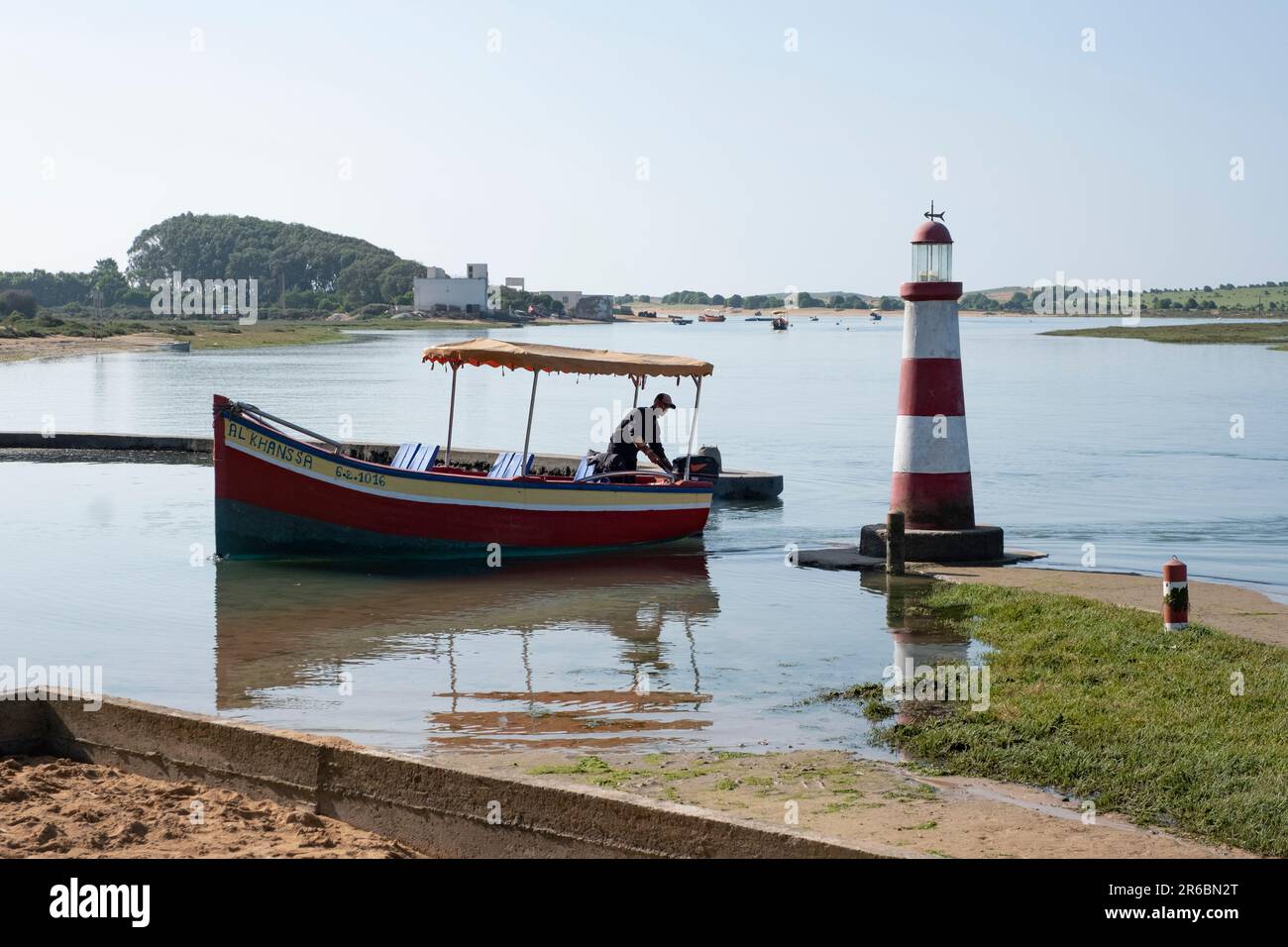 A man mooring his boat at the waterside entrance to Ostrea II oyster restaurant near Oualidia, Morocco Stock Photo