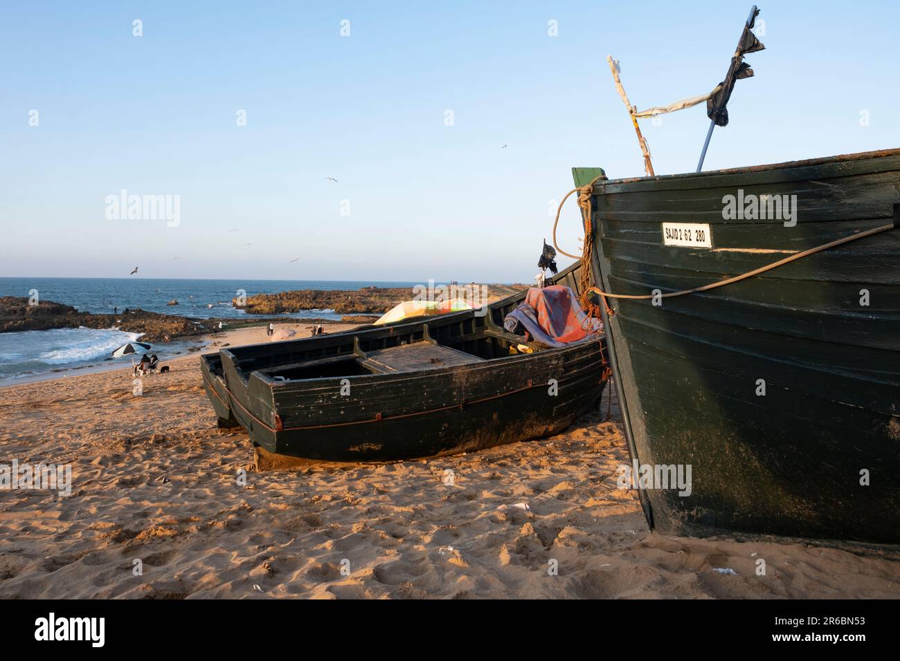 Fishing boats on the sandy beach at Oualidia in Morocco in the warm orange afternoon light Stock Photo