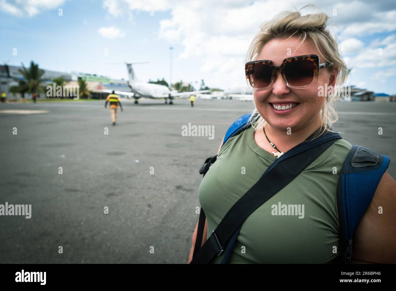 Happy smiling woman on the tarmac of the Zanzibar Airport in Tanzania, just after landing Stock Photo