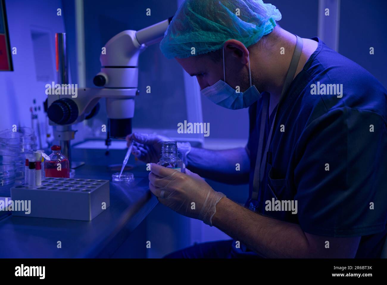 Laboratory technician preparing sample to examine under microscope