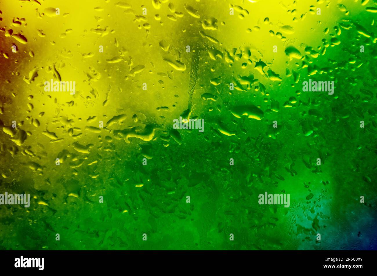 Glass with rain drops in rainbow colors. Raindrops on window closeup ...