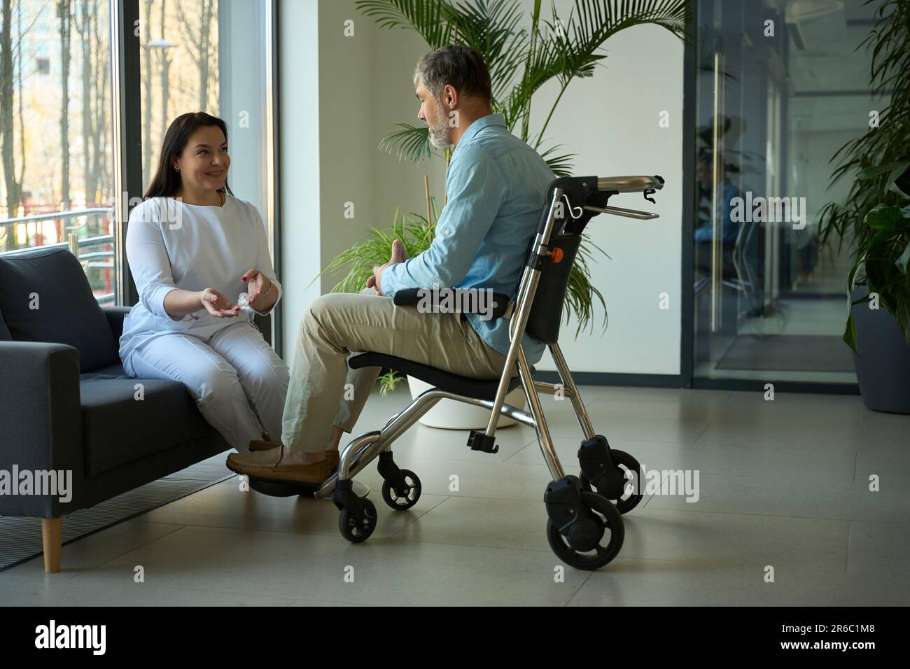 Patient in wheelchair communicating with nurse on couch Stock Photo Alamy