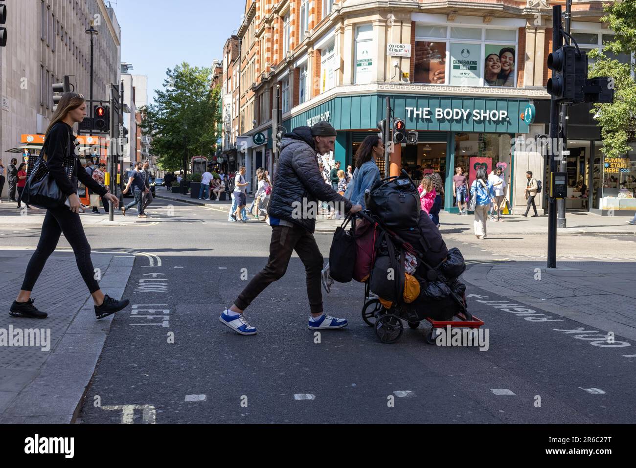 Homeless man pushes a trolly containing his belongings along Oxford Street, in the West End of London, England, United Kingdom Stock Photo
