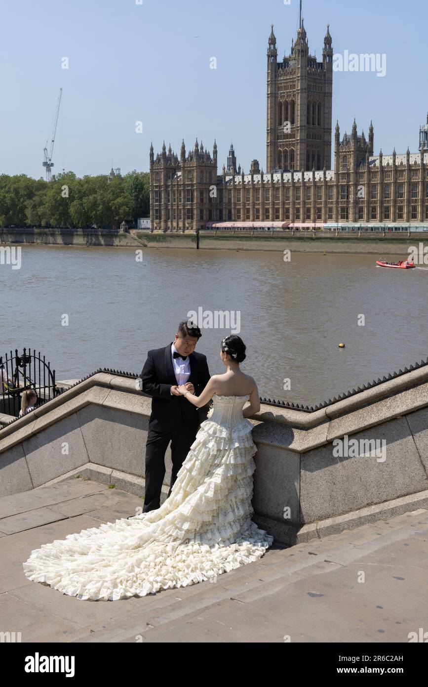 Chinese newly wed couple having their wedding photograph taken opposite the Houses of Parliament, Westminster, London, England, UK Stock Photo