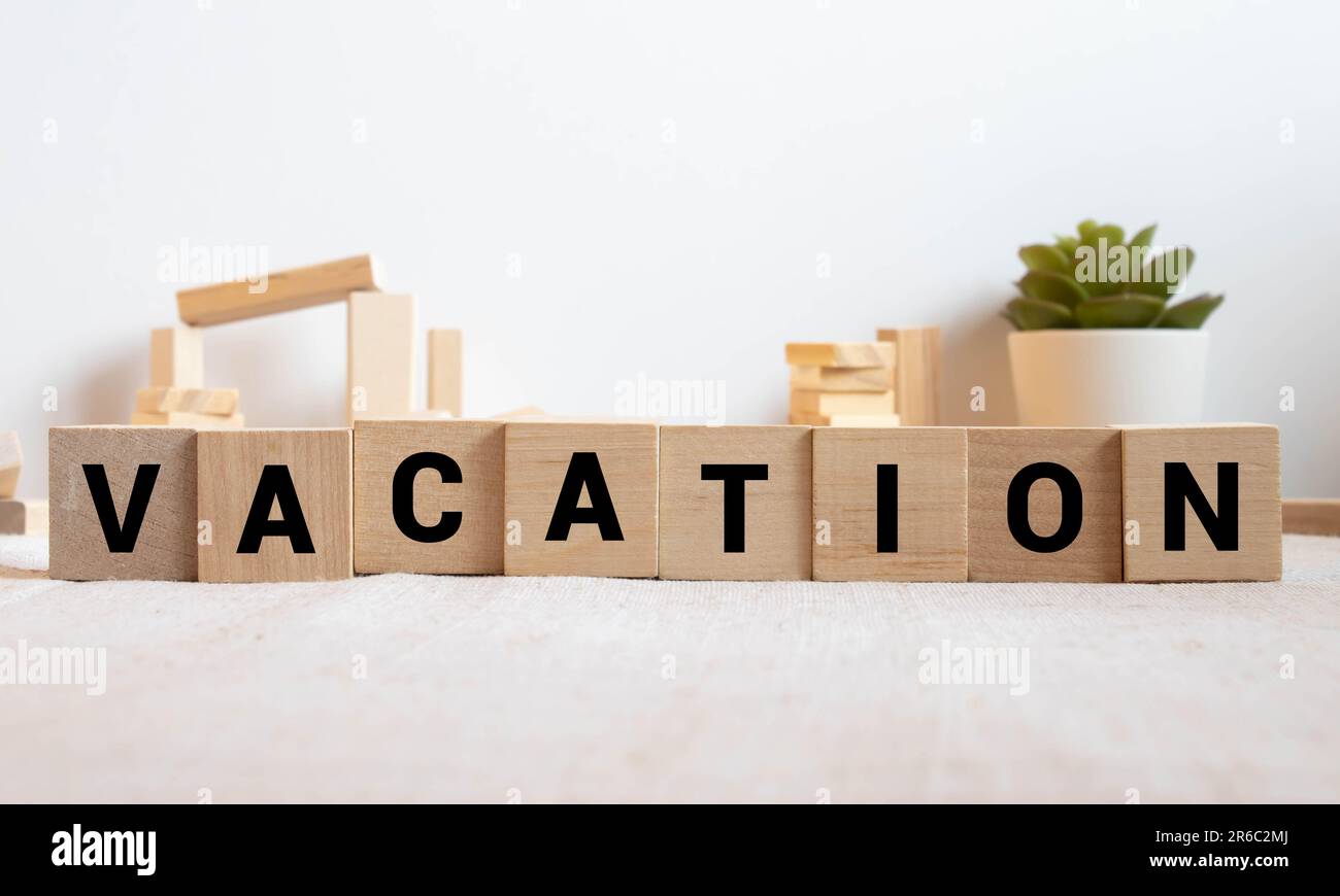 word vacation written in small wooden alphabet cubes on isolated white