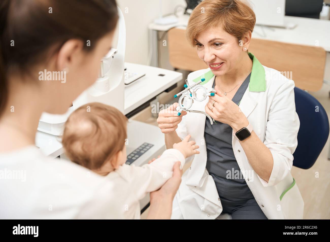 Pediatric ophthalmologist showing ophthalmic device to child Stock