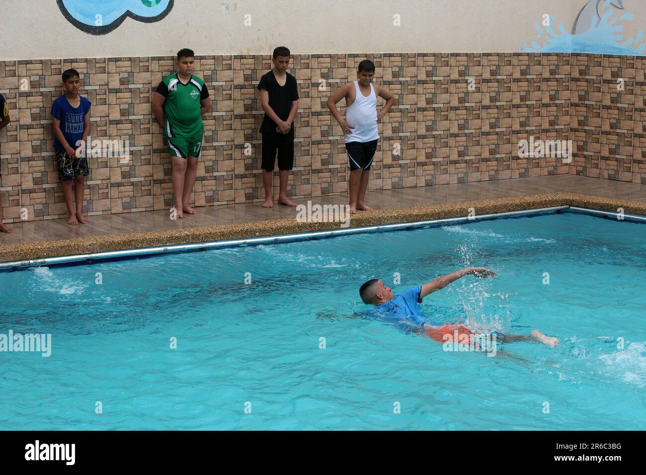 Palestinian children enjoy themselves in a cold water pool during hot