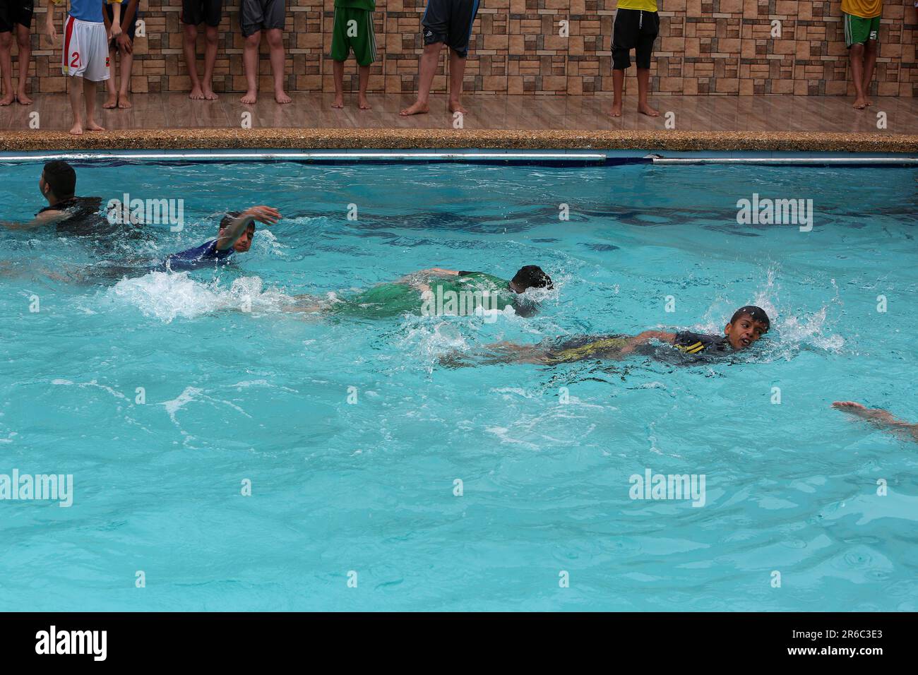 Palestinian children enjoy themselves in a cold water pool during hot