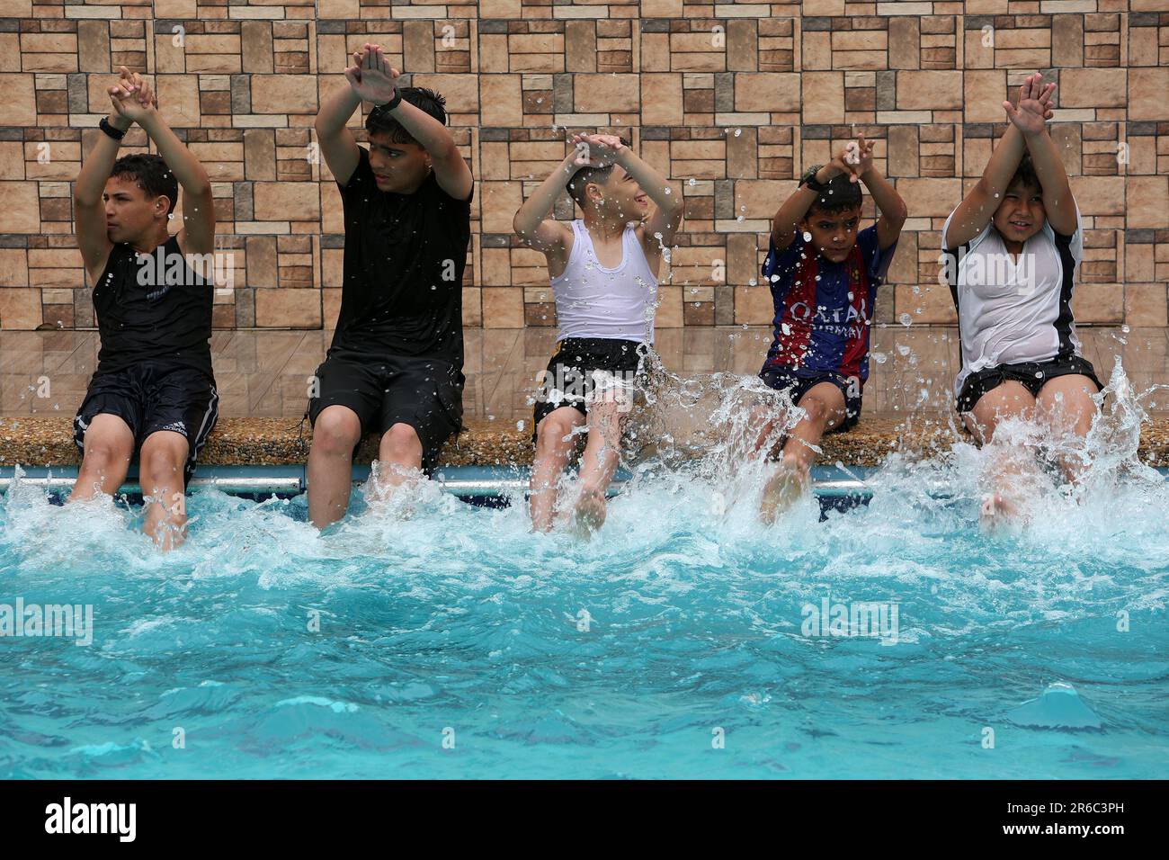 Palestinian children enjoy themselves in a cold water pool during hot