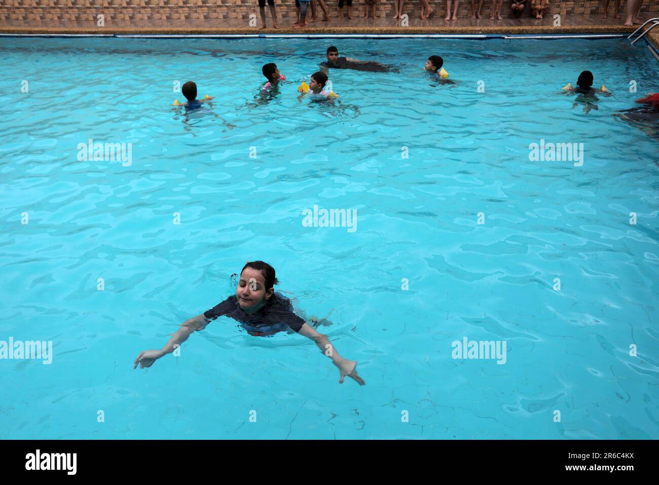 Palestinian children enjoy themselves in a cold water pool during hot