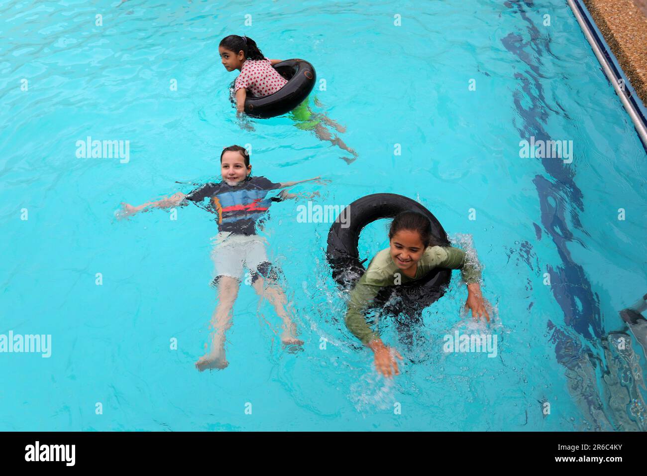 Palestinian children enjoy themselves in a cold water pool during hot