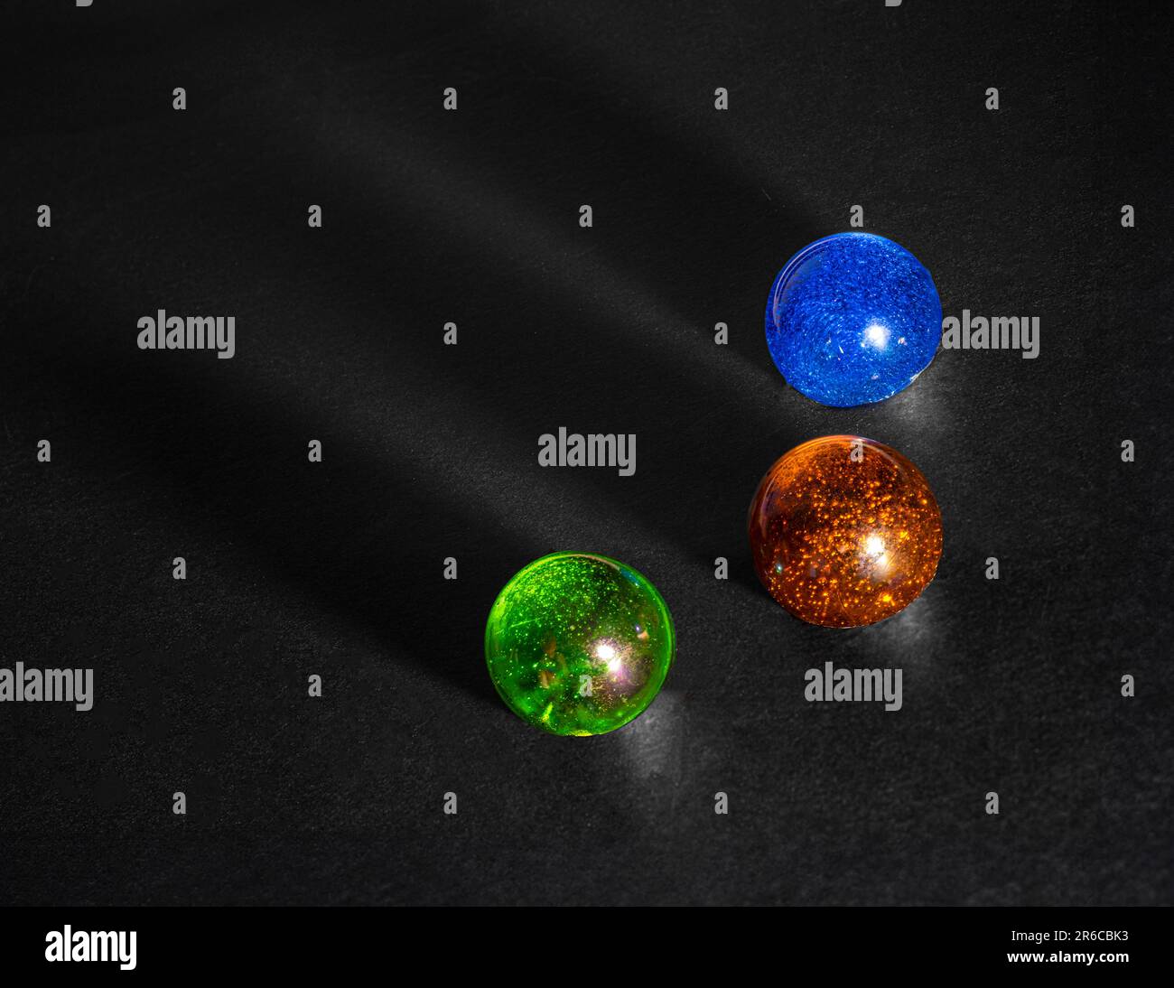 Three glass balls on black background, with shadows. Stock Photo