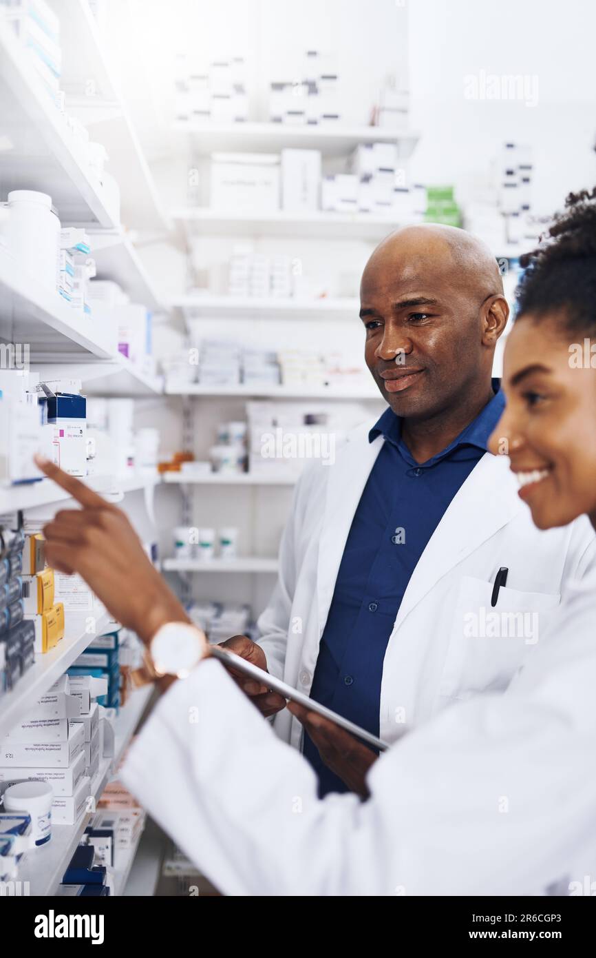 Working together for your wellbeing. two pharmacists doing inventory in ...