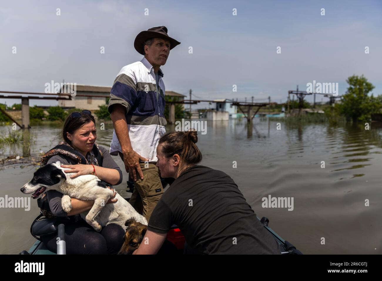 Kherson, Ukraine. 8th June, 2023. Knowable Truth pastor Bill Rigsby, 61, of Texas, pilots the boat while Ukrainian volunteers Iulia Yakovenko, 38, bottom right, and Inna Shuparska hold the dogs they rescued from a rooftop while they navigate to safety from flood waters at Kherson, Ukraine on June 8, 2023. The Kherson region is experiencing flooding from the Dnipro River after the Nova Kakhovka Dam was blown up. The Russians have been shelling the Kherson region during ongoing civilian evacuations. (Credit Image: © Daniel Carde/ZUMA Press Wire) EDITORIAL USAGE ONLY! Not for Commercial USAGE! Stock Photo