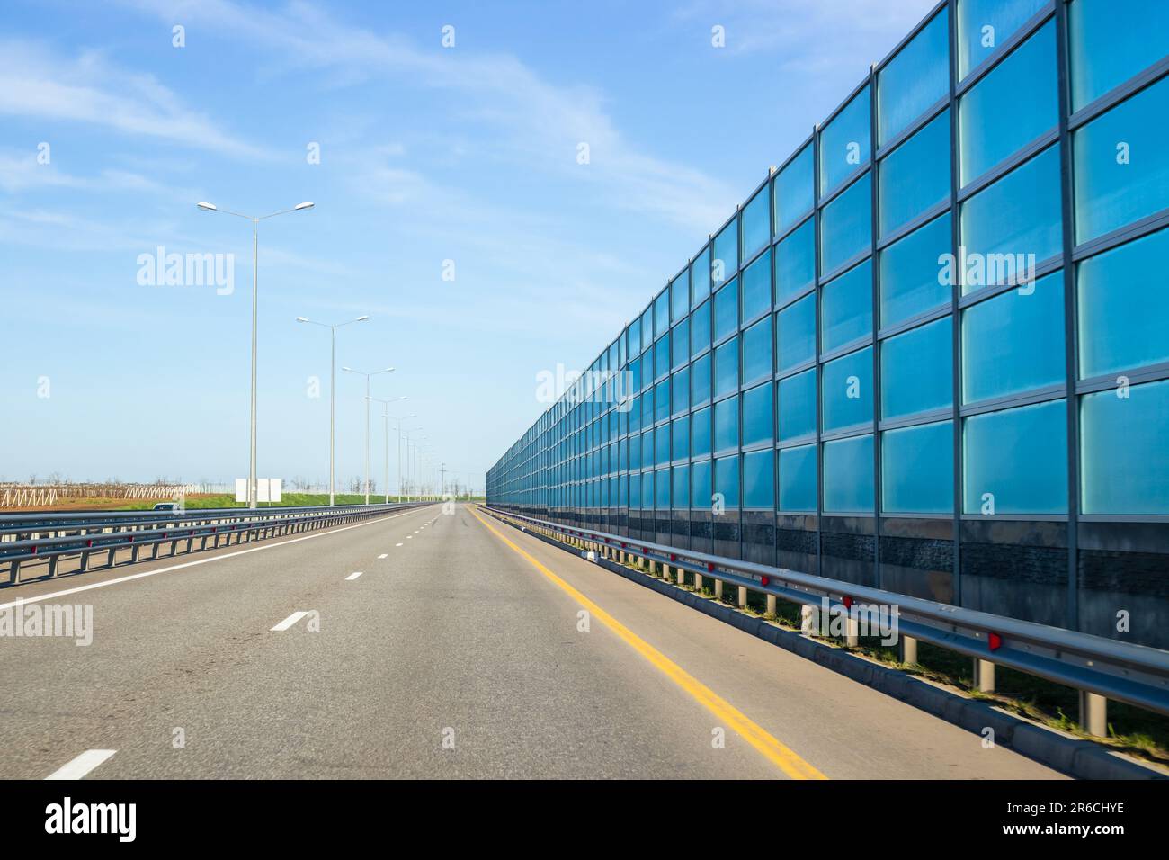 Road with noise reduction screen on the right. Driving on the highway near settlements. Stock Photo