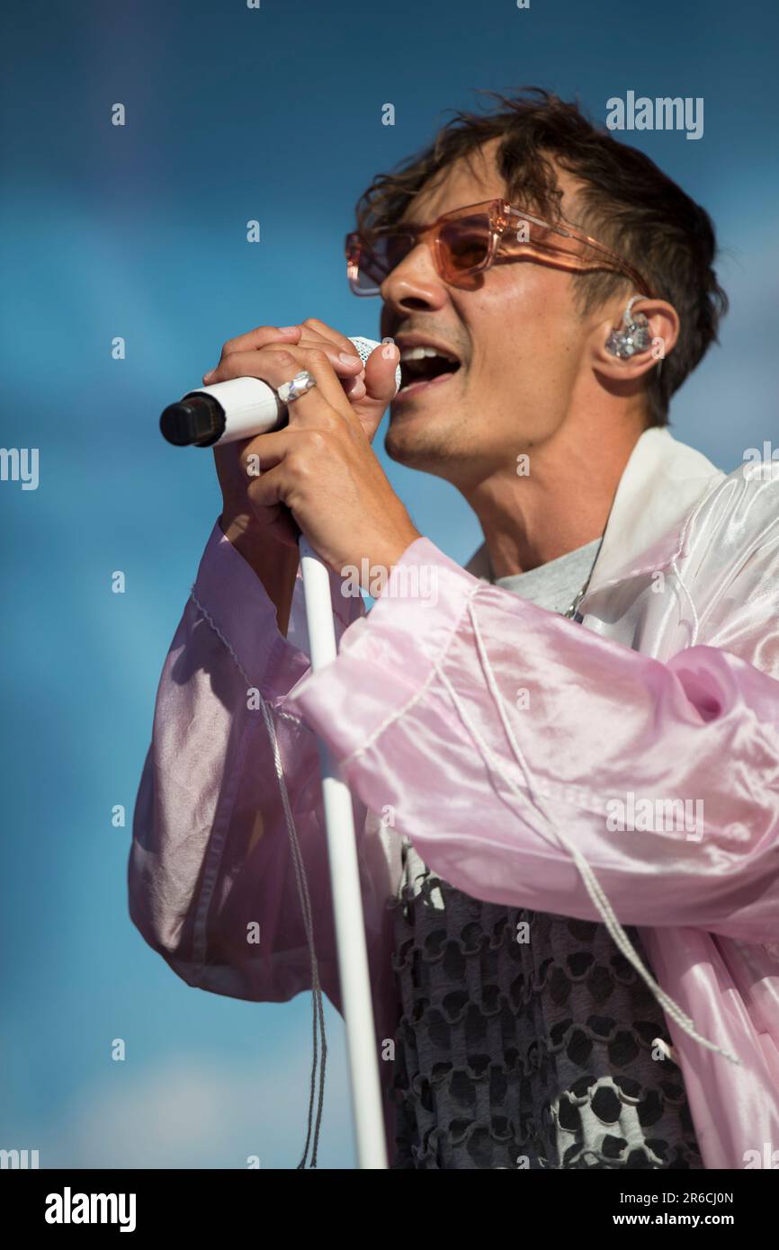 A male vocalist wearing a purple dress and sunglasses sings into a ...