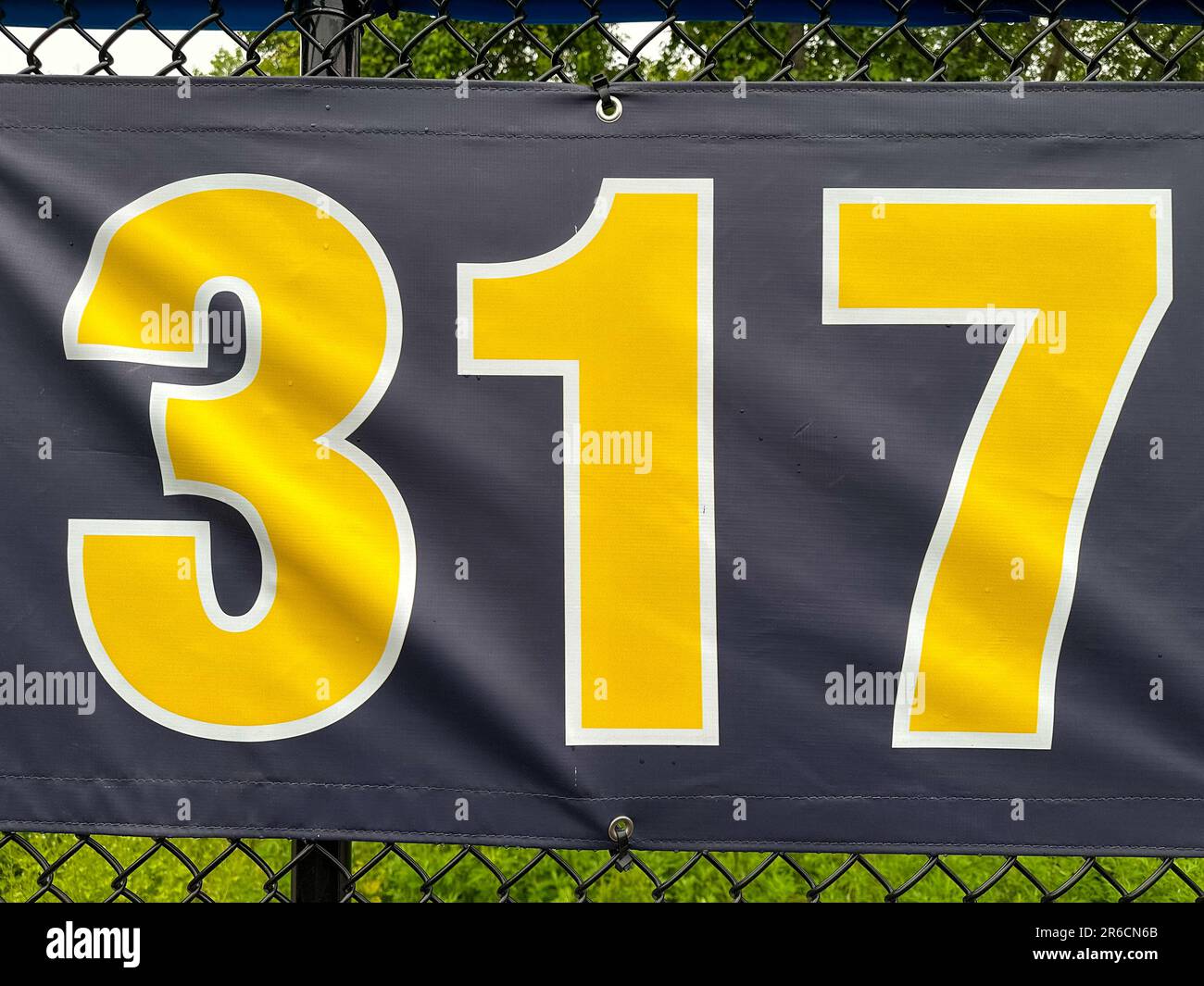 317 foot ft baseball field distance sign in yellow and black mounted on the black vinyl outfield