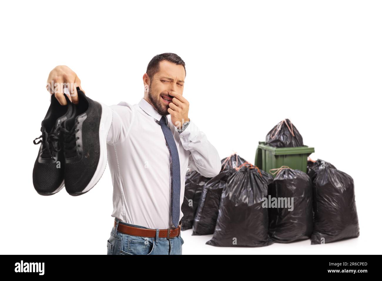 Man holding a pair of smelly trainers in front of waste bins isolated on white background Stock Photo