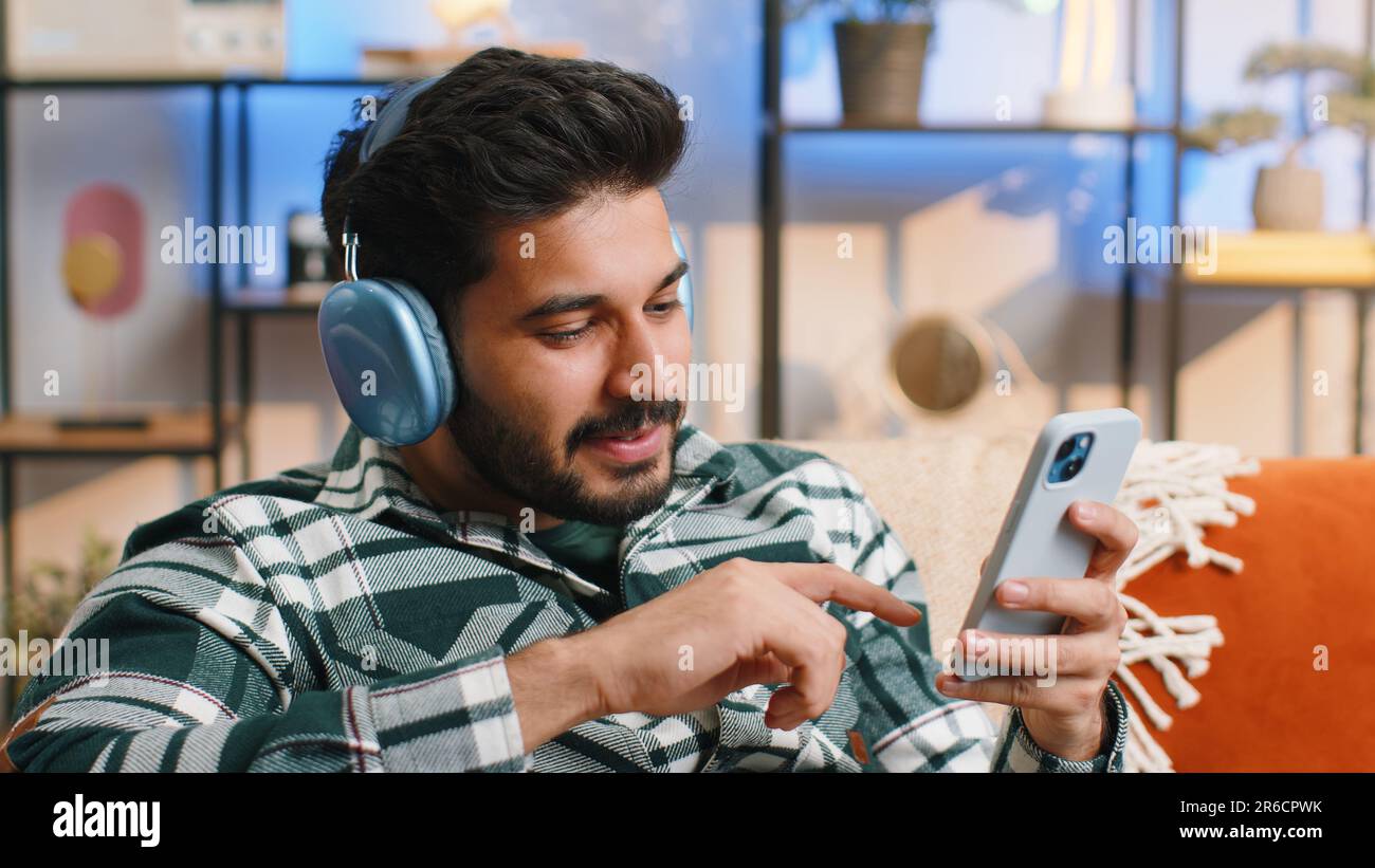 happy-overjoyed-indian-man-in-wireless-headphones-relaxing-sitting-on