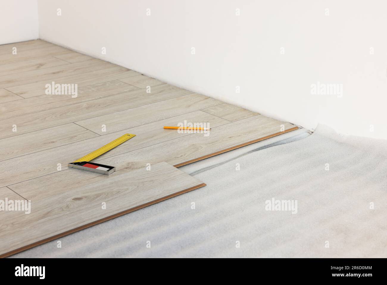 Ruler, pencil and parquet planks on floor in room prepared for ...