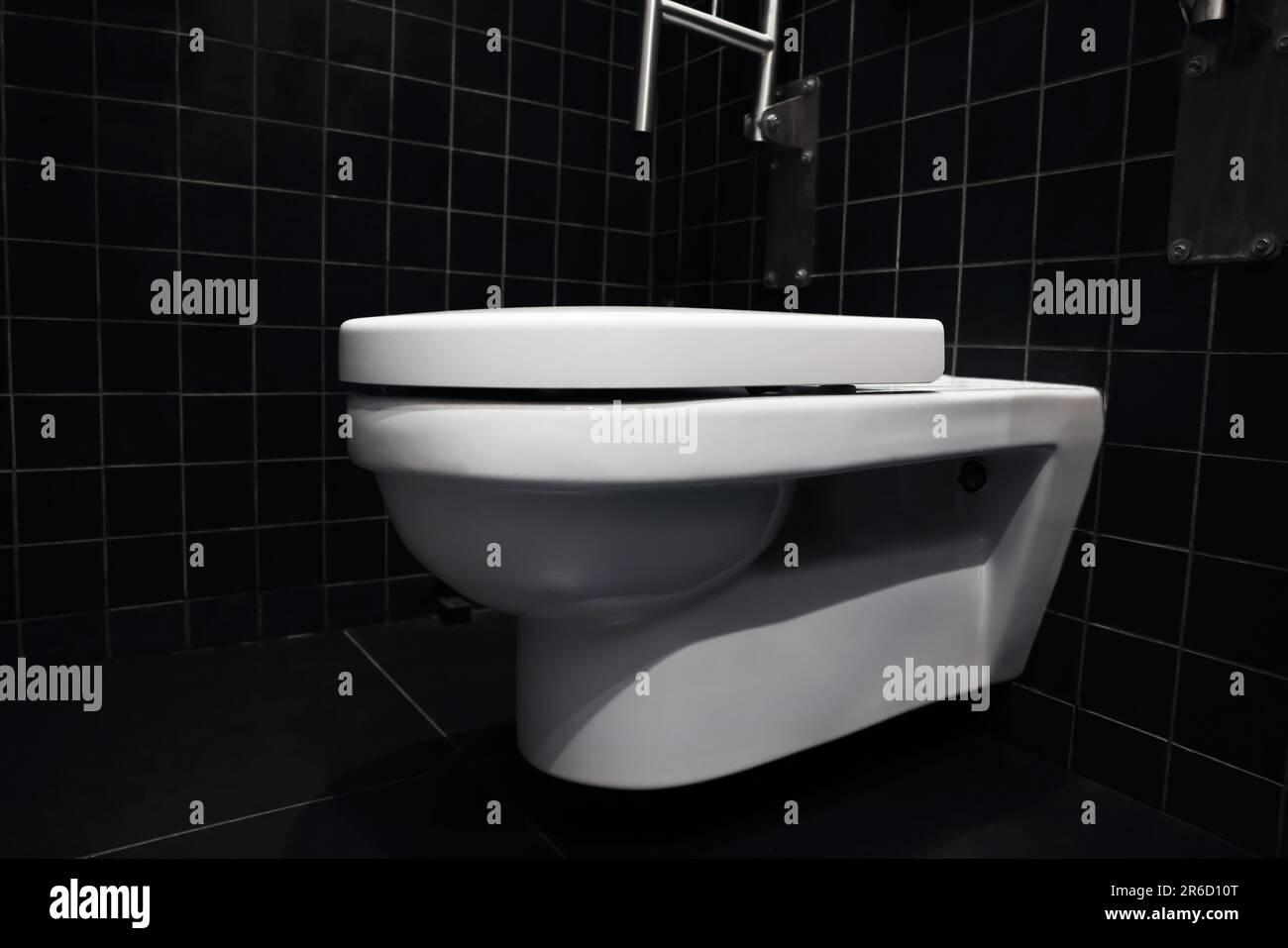 Clean ceramic toilet bowl near tiled wall indoors Stock Photo - Alamy