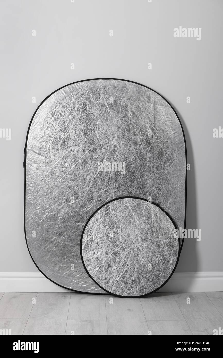 Studio reflectors near grey wall in room. Professional photographer's