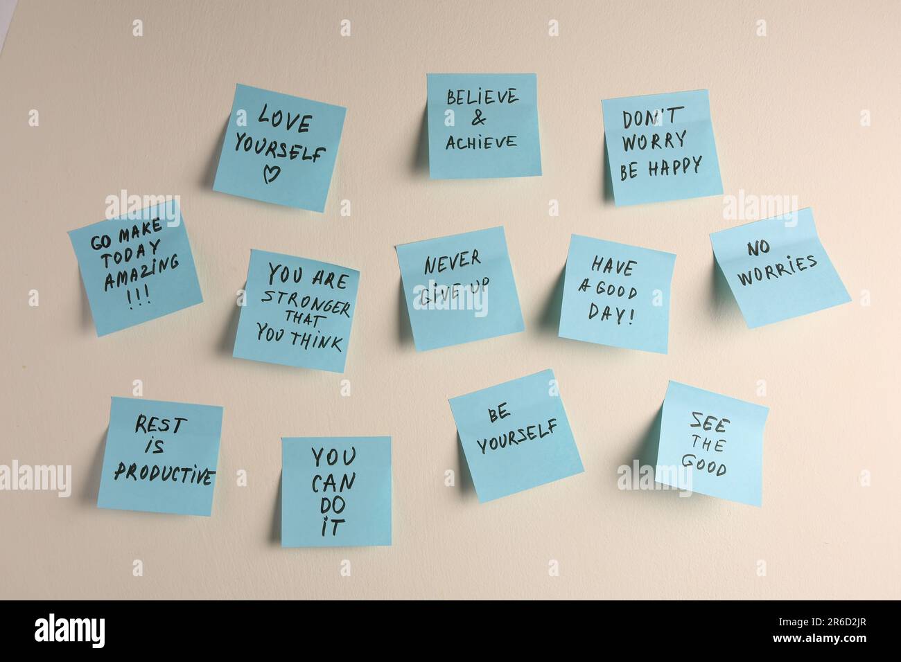 Paper notes with life-affirming phrases on white wall Stock Photo