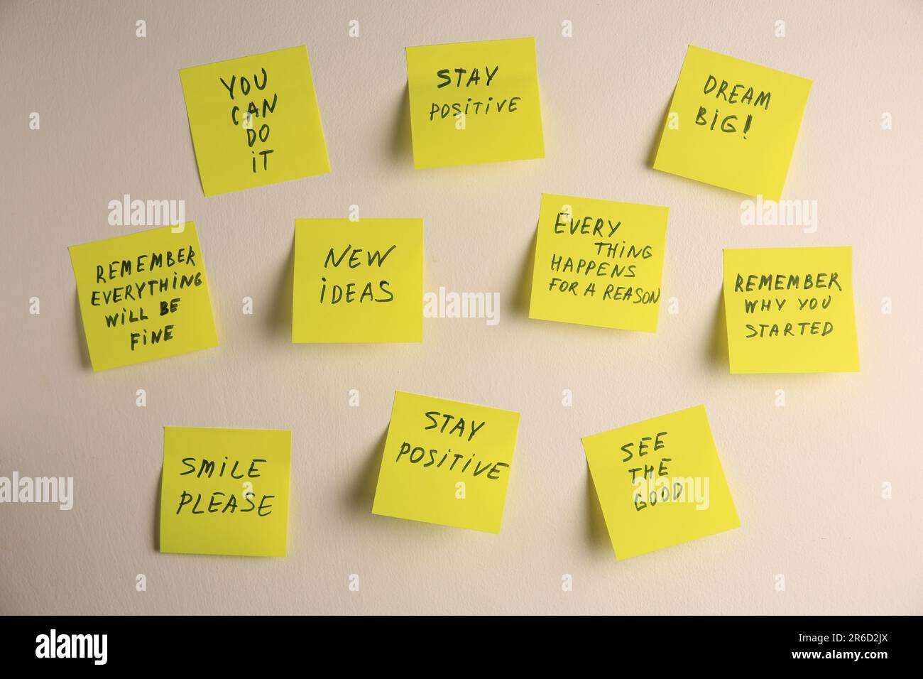 Paper notes with life-affirming phrases on white wall Stock Photo