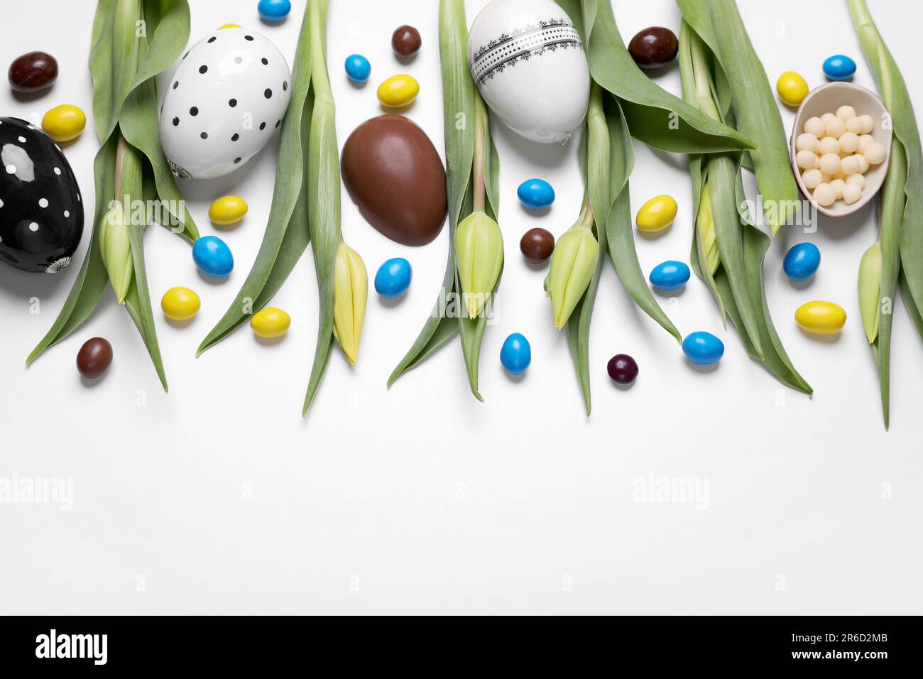 Flat lay composition with tulips, chocolate eggs and candies on white ...