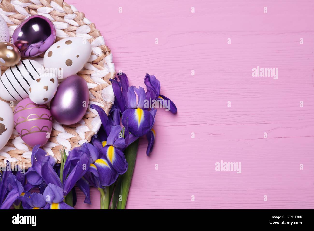 Flat lay composition with festively decorated Easter eggs and iris flowers on pink wooden background. Space for text Stock Photo