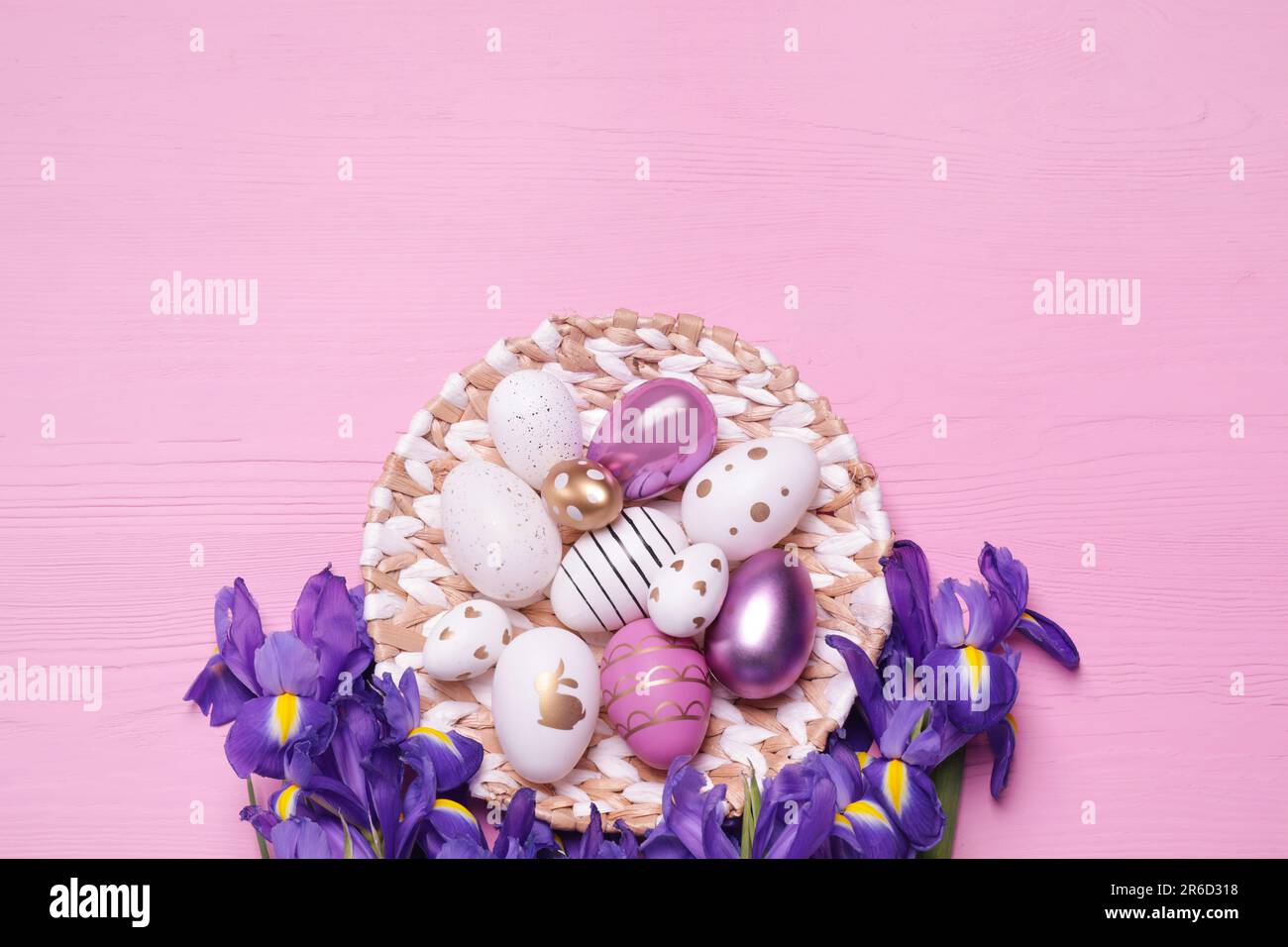 Flat lay composition with festively decorated Easter eggs and iris flowers on pink wooden background Stock Photo