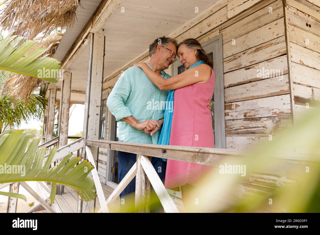 Loving caucasian senior husband and wife hugging and looking at each other while standing in balcony Stock Photo