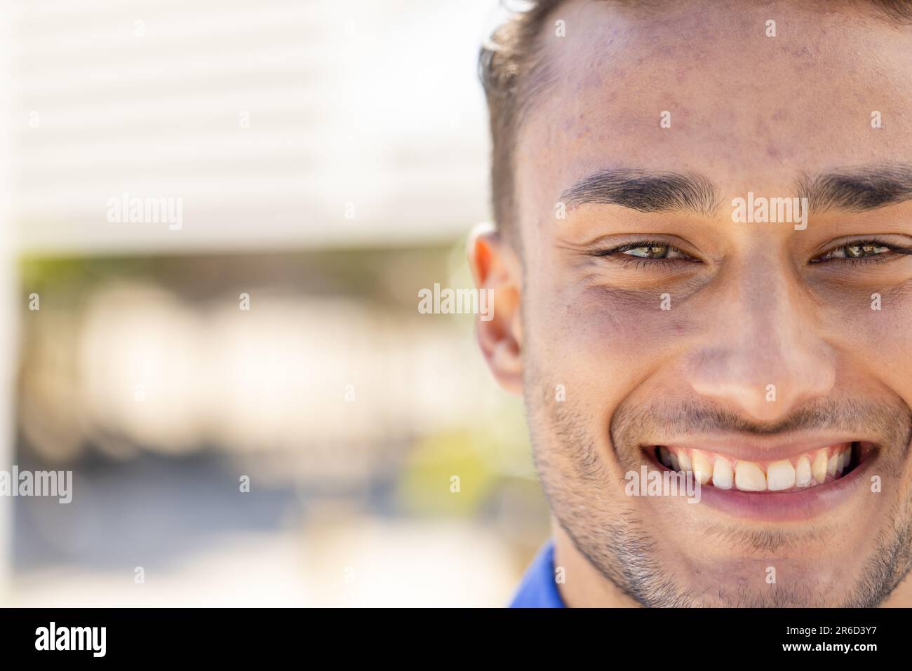 Close-up portrait of handsome caucasian young man with brown eyes smiling and looking at camera Stock Photo