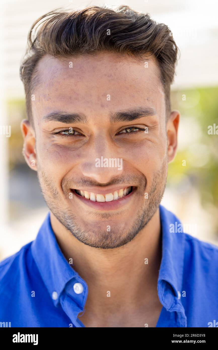 Close-up portrait of handsome caucasian young man with brown eyes smiling and looking at camera Stock Photo