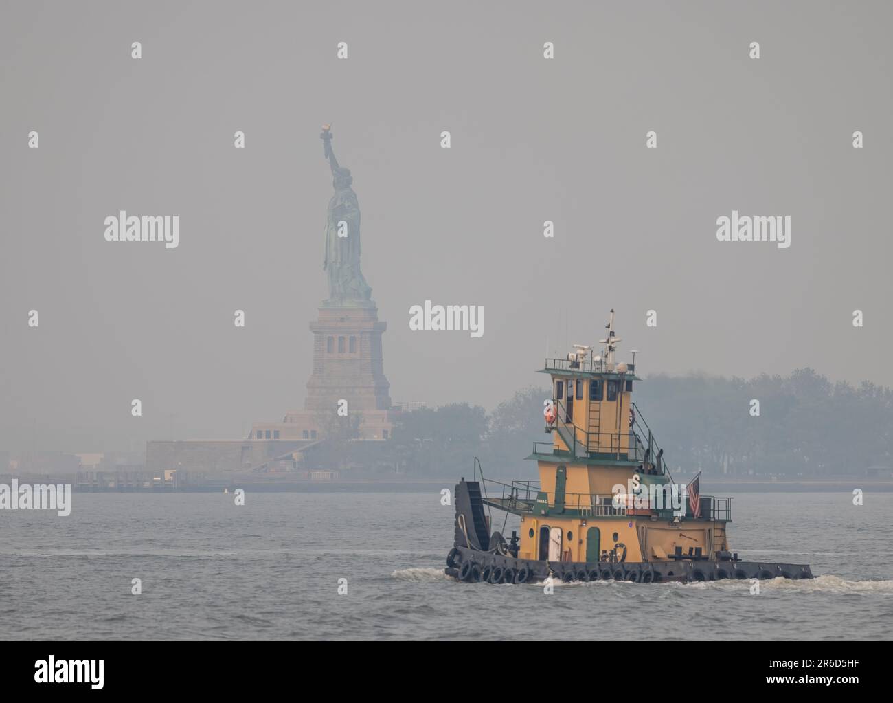 NEW YORK, N.Y. – June 7, 2023: The Statue of Liberty is seen under a hazy sky as smoke from Canadian wildfires reduced air quality in New York City. Stock Photo