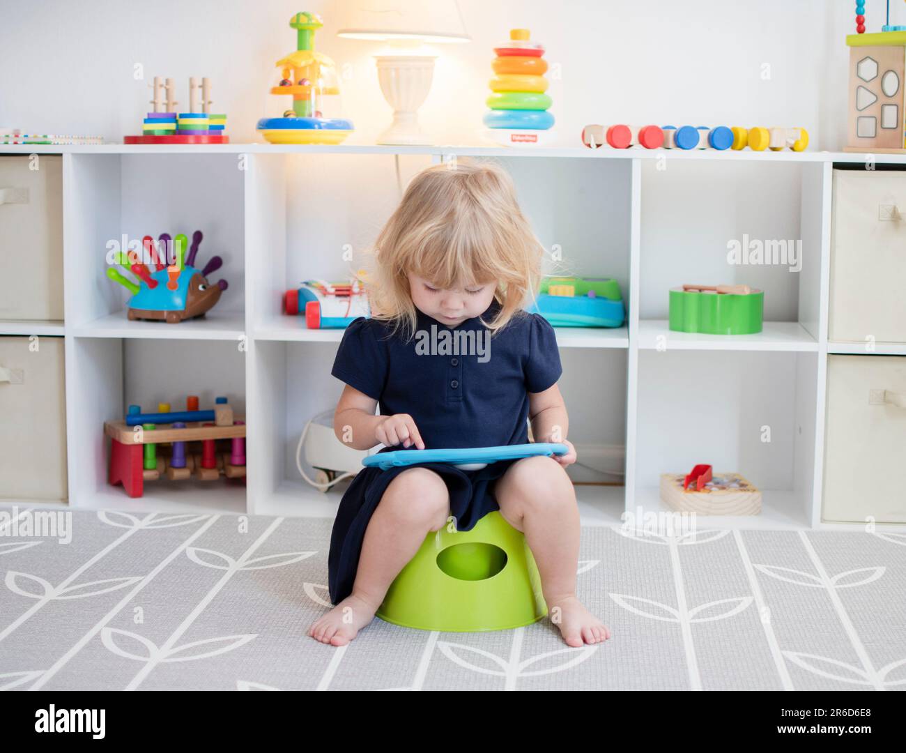 Toddler girl sitting on a potty with the tablet. Potty training. Toilet training Stock Photo