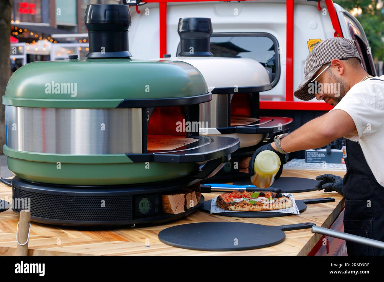 A chef drizzles a ring of olive oil on a neopolitan pizza made in a Gozney Dome portable pizza oven at a CG Pizza pop-up pizza event. Stock Photo
