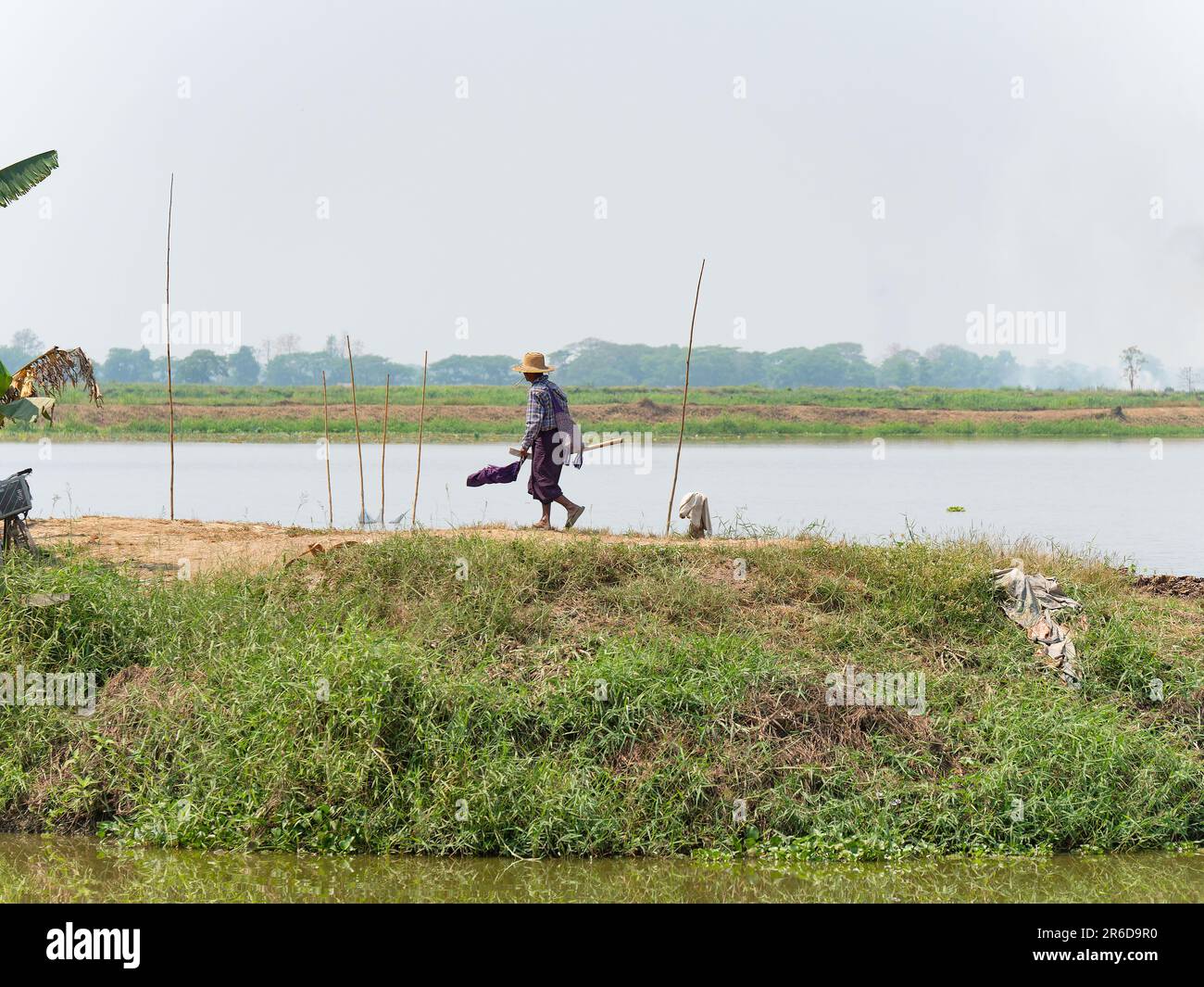 Farmer walking on an embankment between fish ponds at the Irrawaddy Ragion of Myanmar. Stock Photo