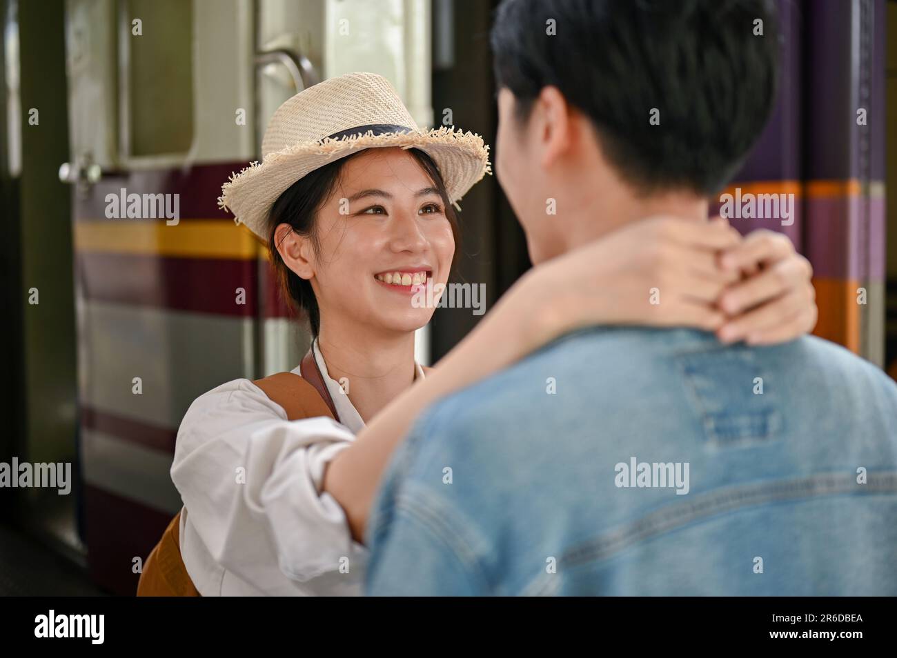 A beautiful and lovely young Asian girl embraces the neck of her ...