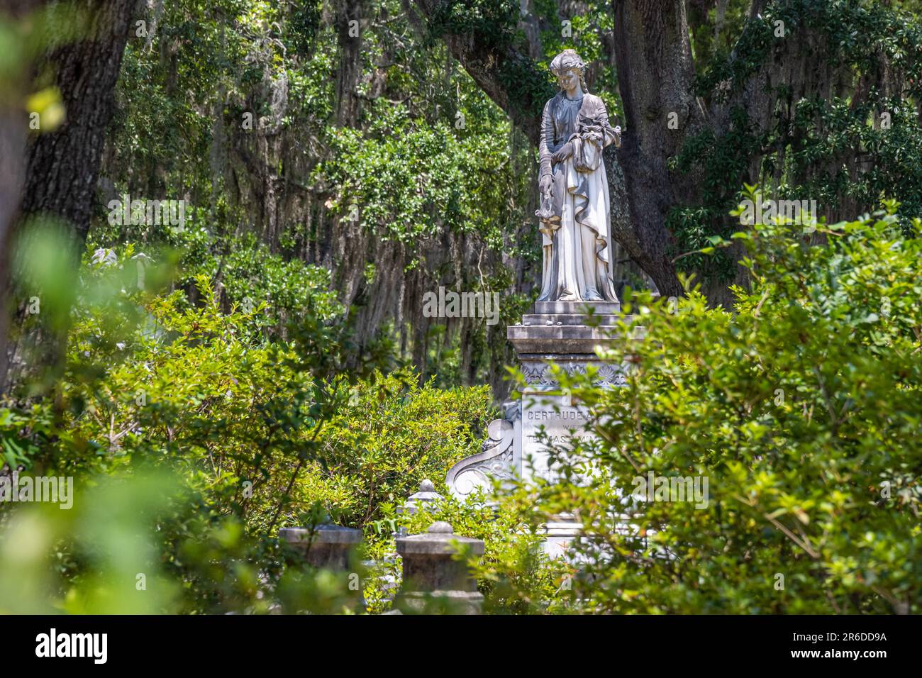 Grave monument statue of a woman amidst Spanish moss draped Southern